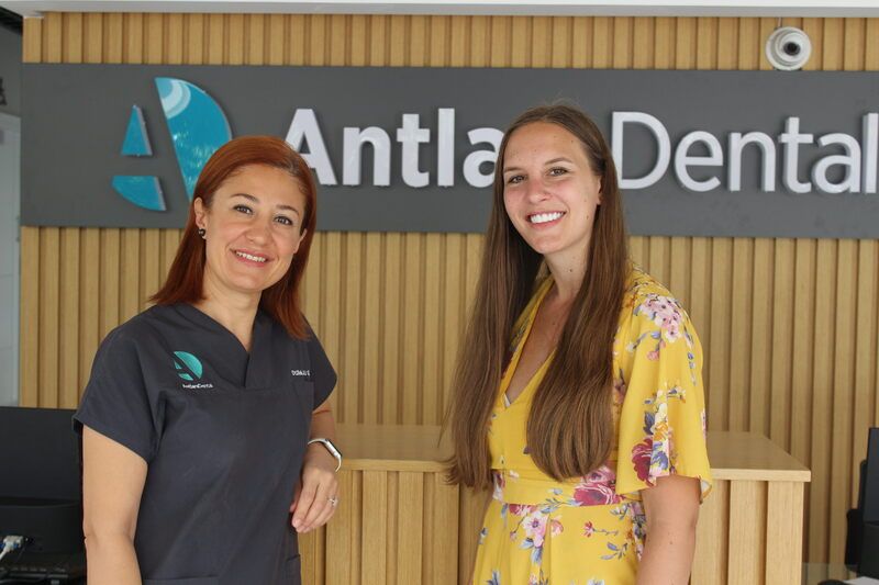 patinet smiles in front of antlara dental clinic logo in antalya turkey